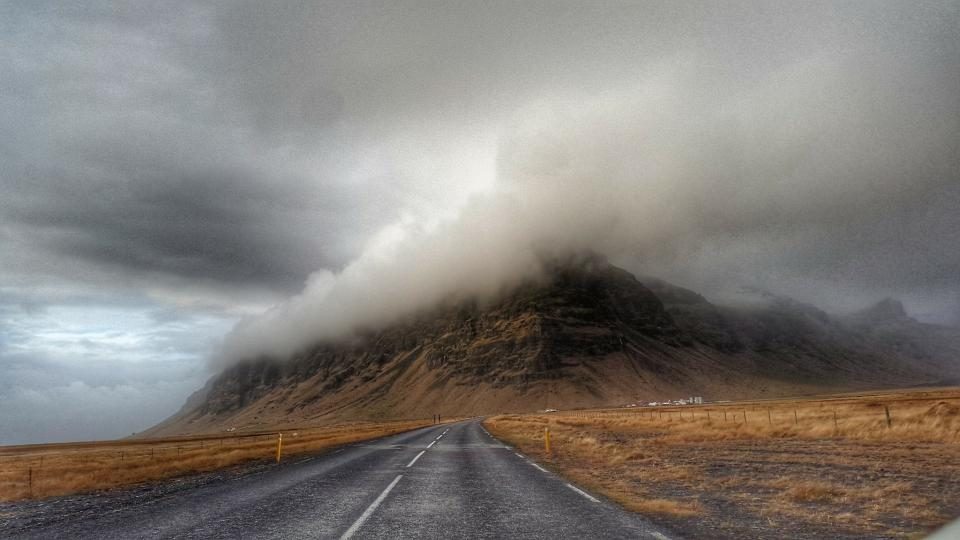 A road leading into fog and mountains